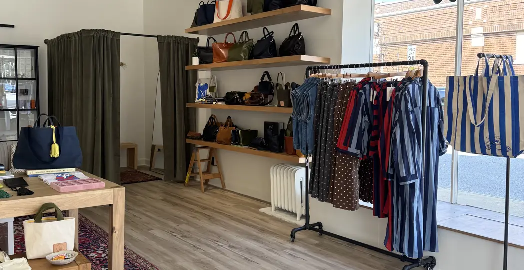 store with a clothing rack, shelves of purses, and a dressing room