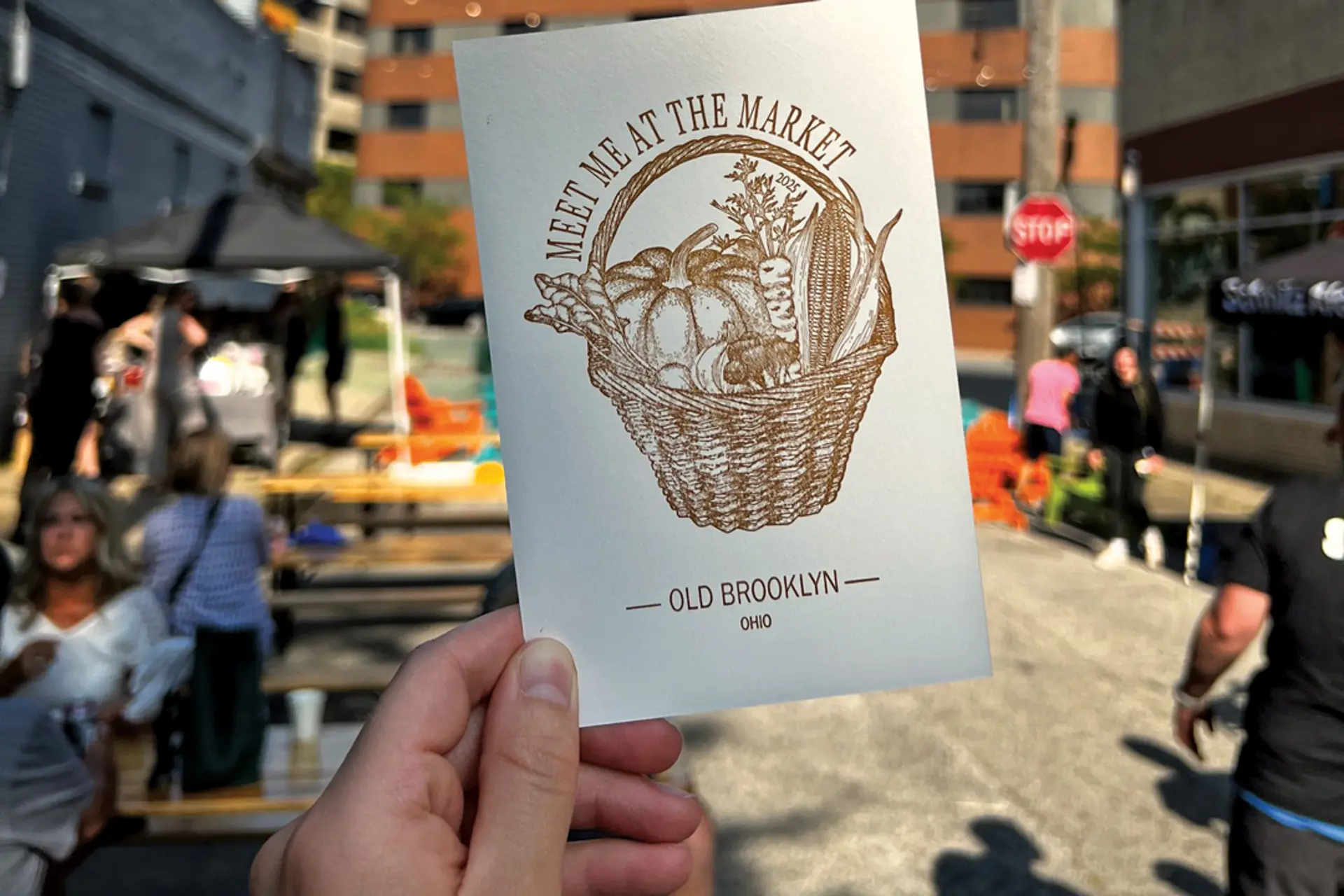 a hand holding a small piece of paper with "meet me at the market" printing on it