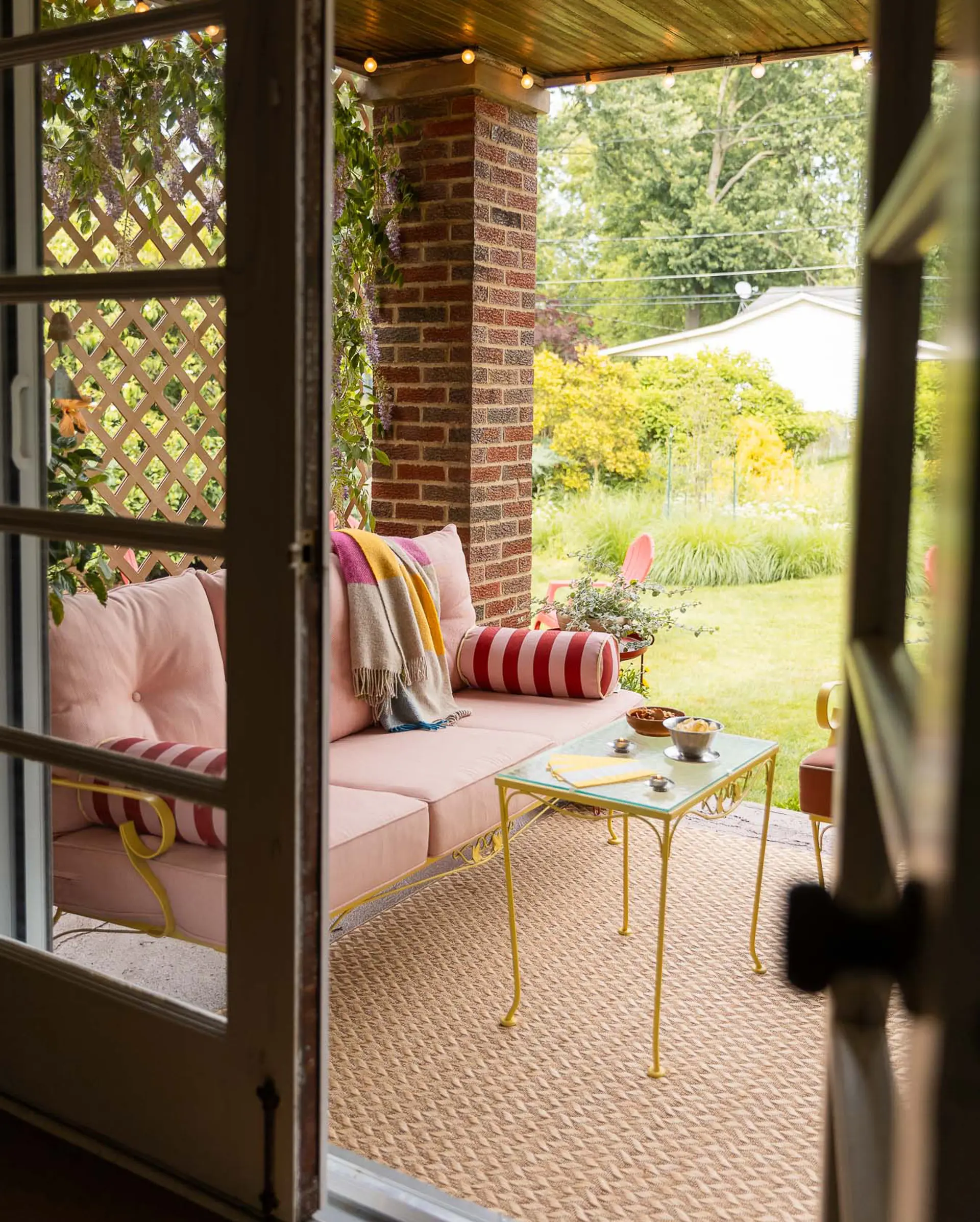 porch with pink couch and string lights
