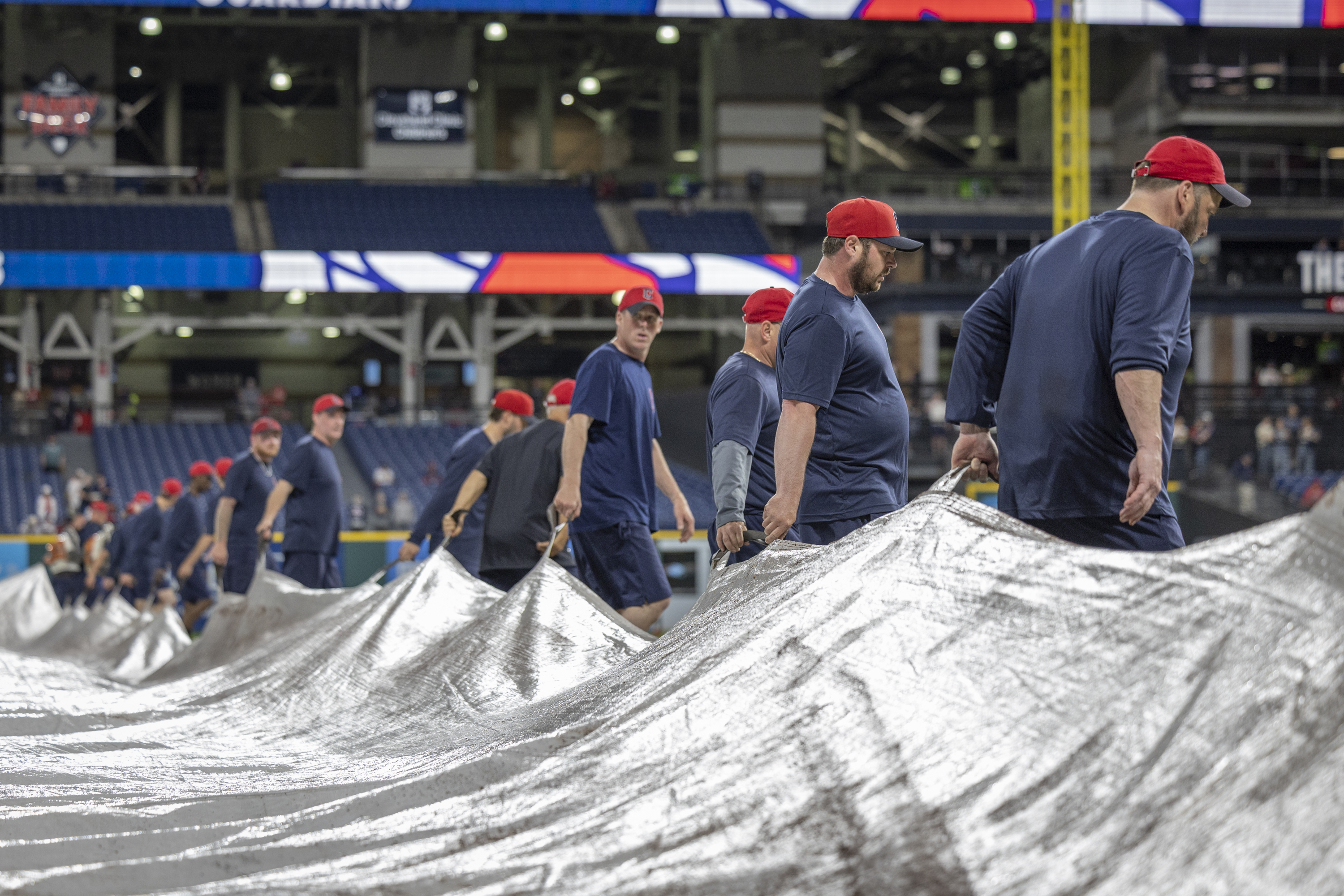 Guardians' groundskeepers work together to unroll the tarp.