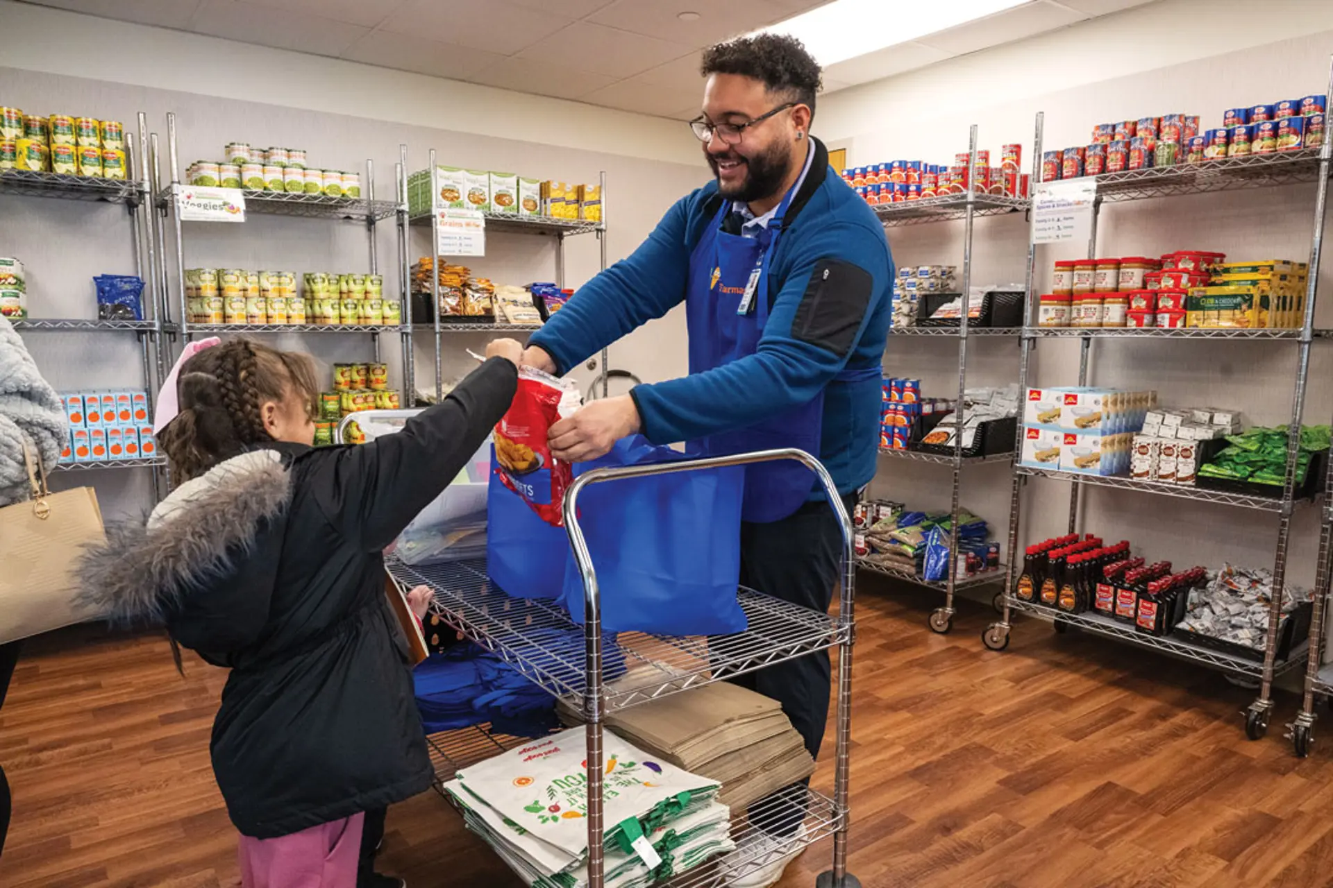 A man helps a child put something in a grocery bag