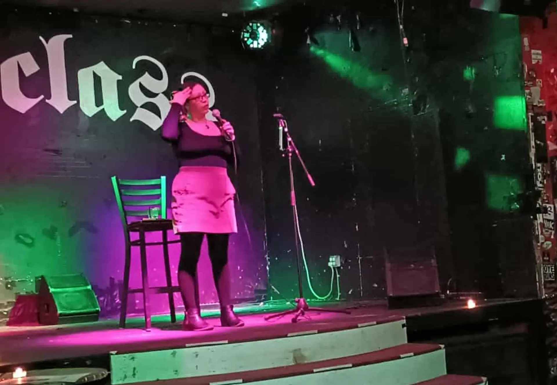 Woman holds a microphone onstage speaking at an event