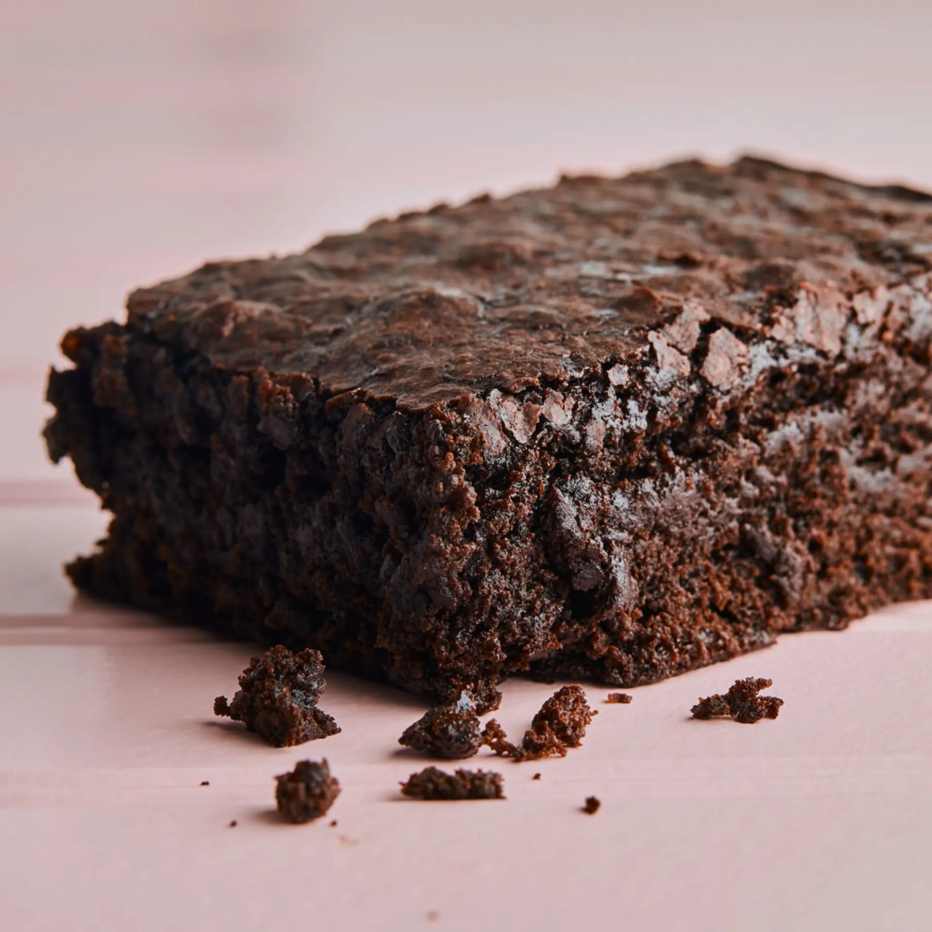 Square brownie slice on pink background.