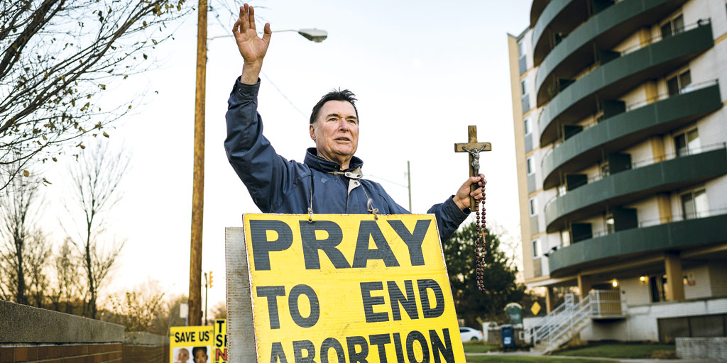 ARMED WITH A 30-YEAR-OLD CRUCIFIX, SOKOL BELIEVES HE’S SAVING LIVES BY PROTESTING ABORTION PROVIDERS.