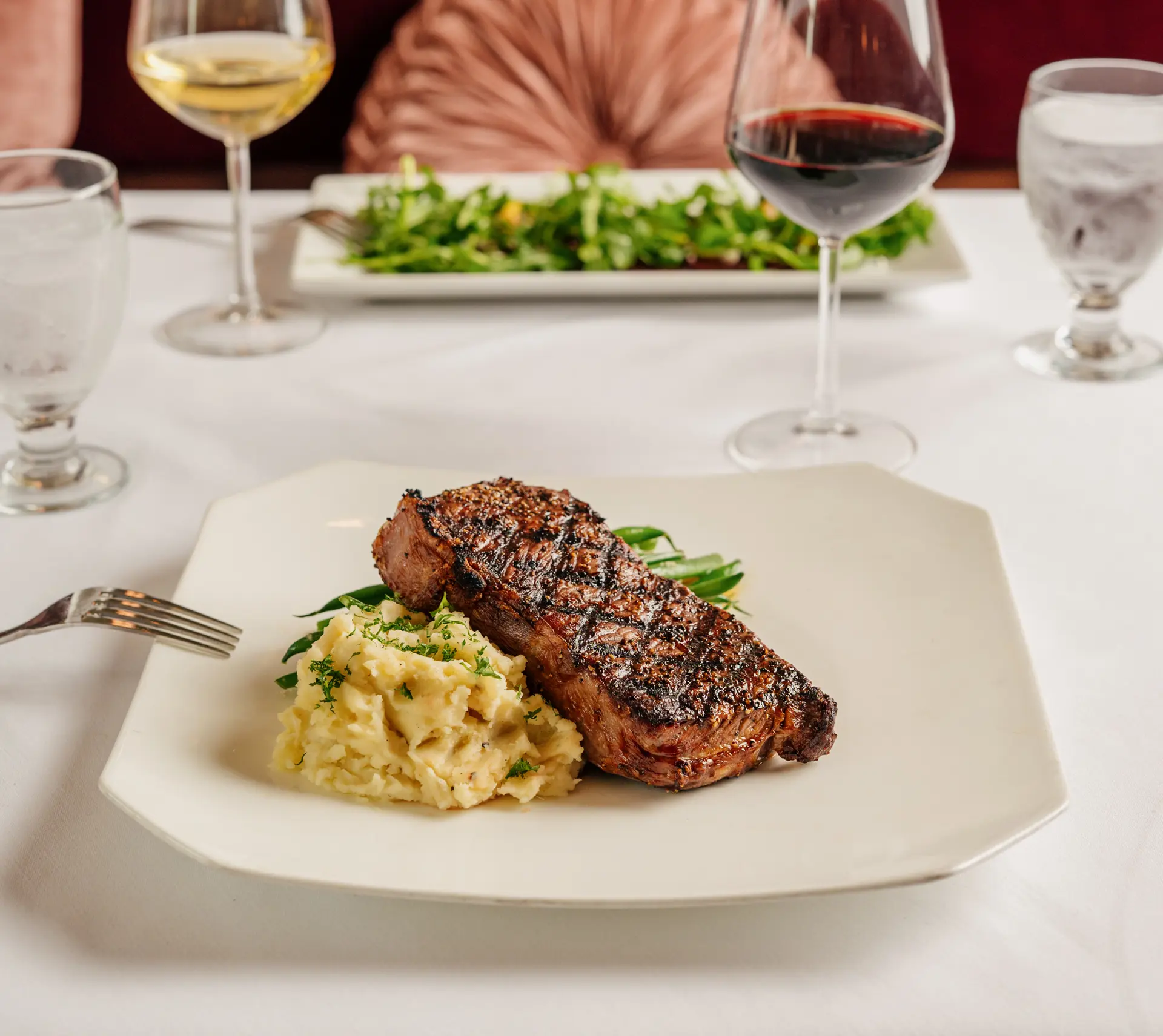 Steak and mashed potatoes on a white plate.