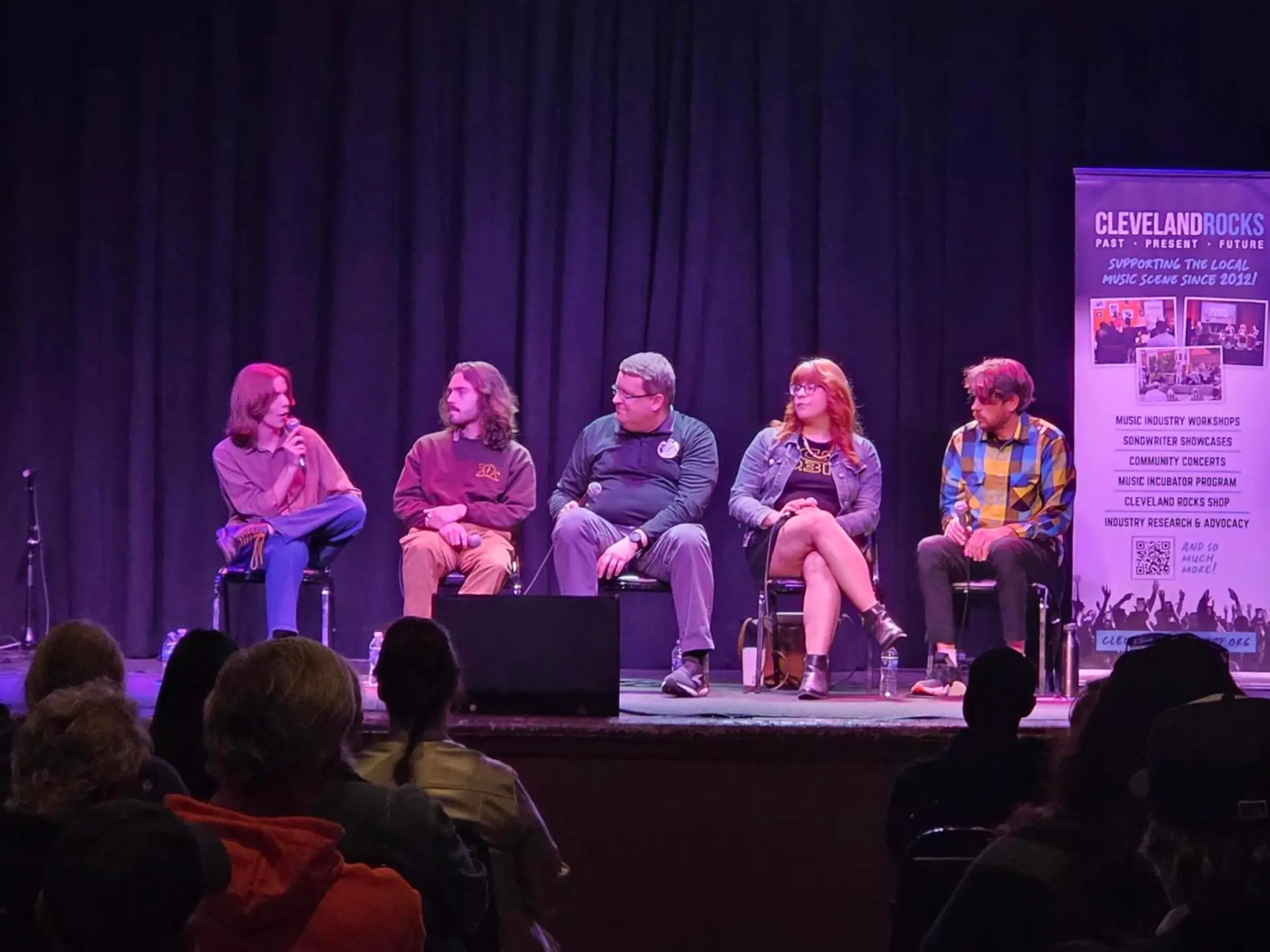 A group of people sitting onstage in a panel.