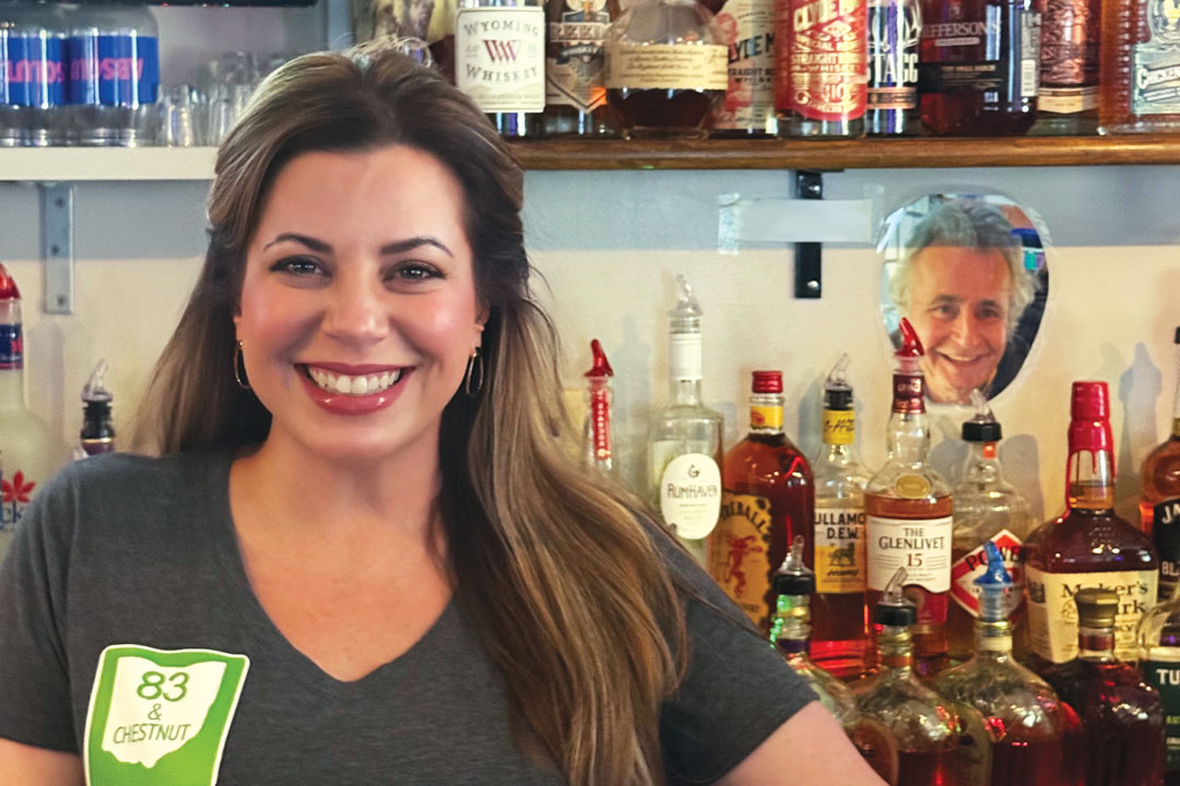A woman smiling behind a bar