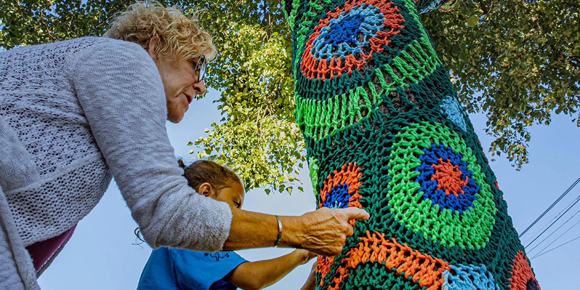 Carol Hummel installing yarn artwork on a tree.