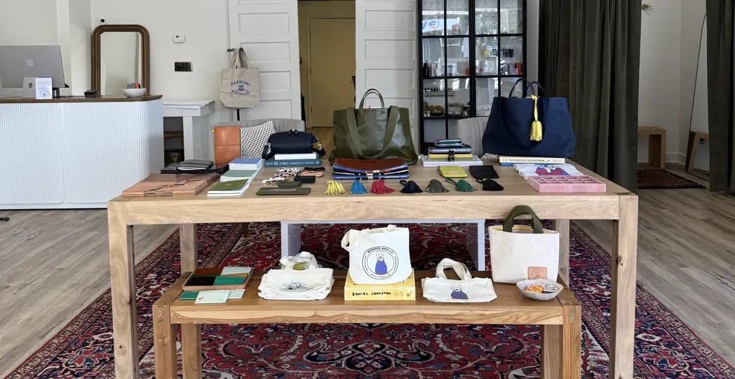display table at store with purses, wallets, notebooks, and other leather goods