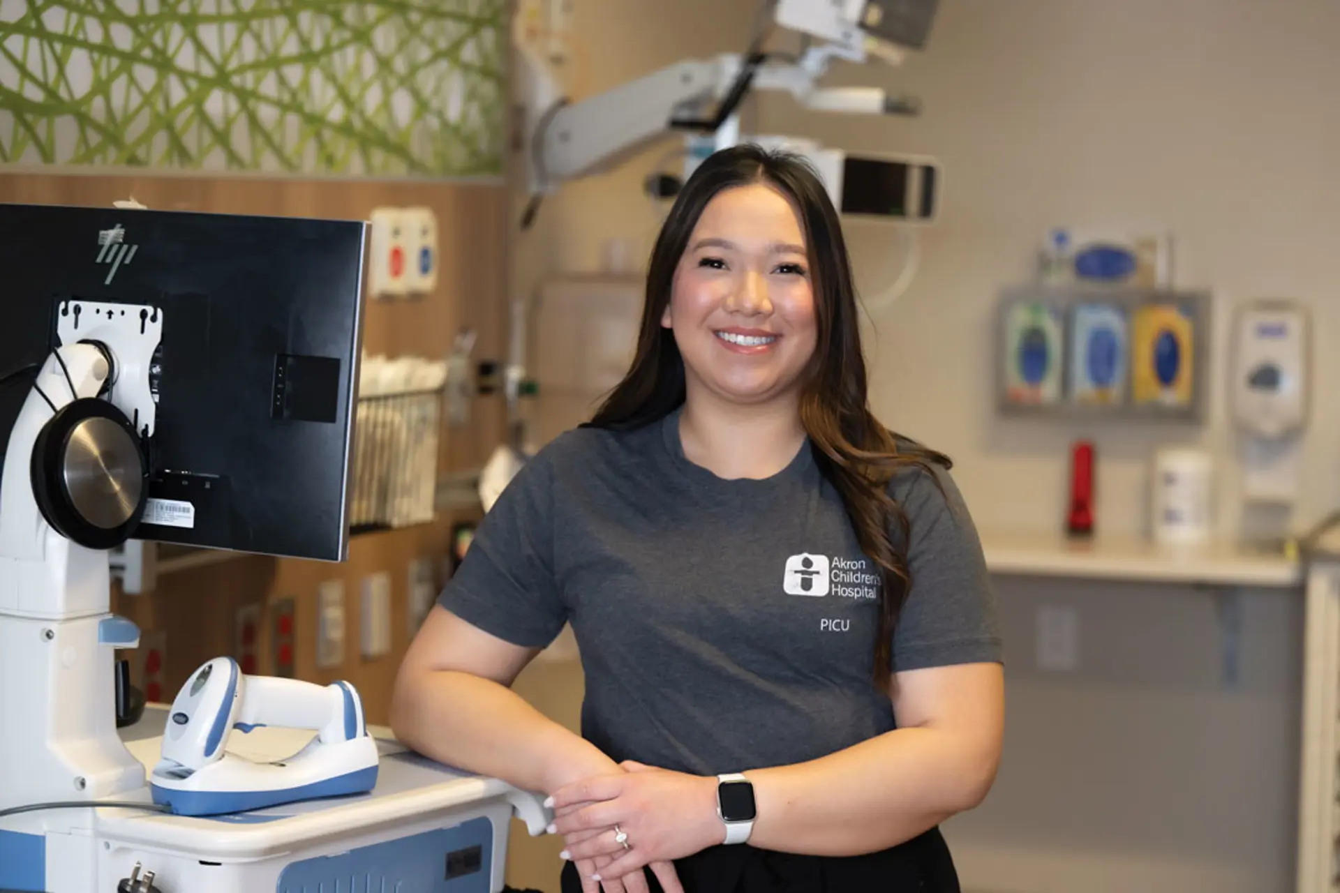 A registered nurse standing at her work station and smiling