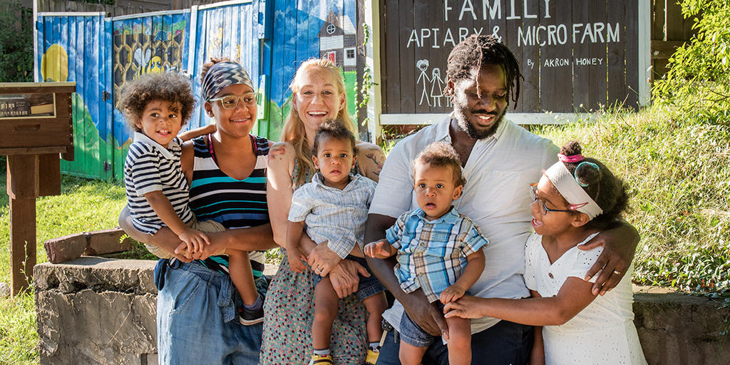 Wesley stands outside one of his apiaries with his family, (left to right) Sam, Bella, Rebecca, Kassian, Loukah and Caedance.