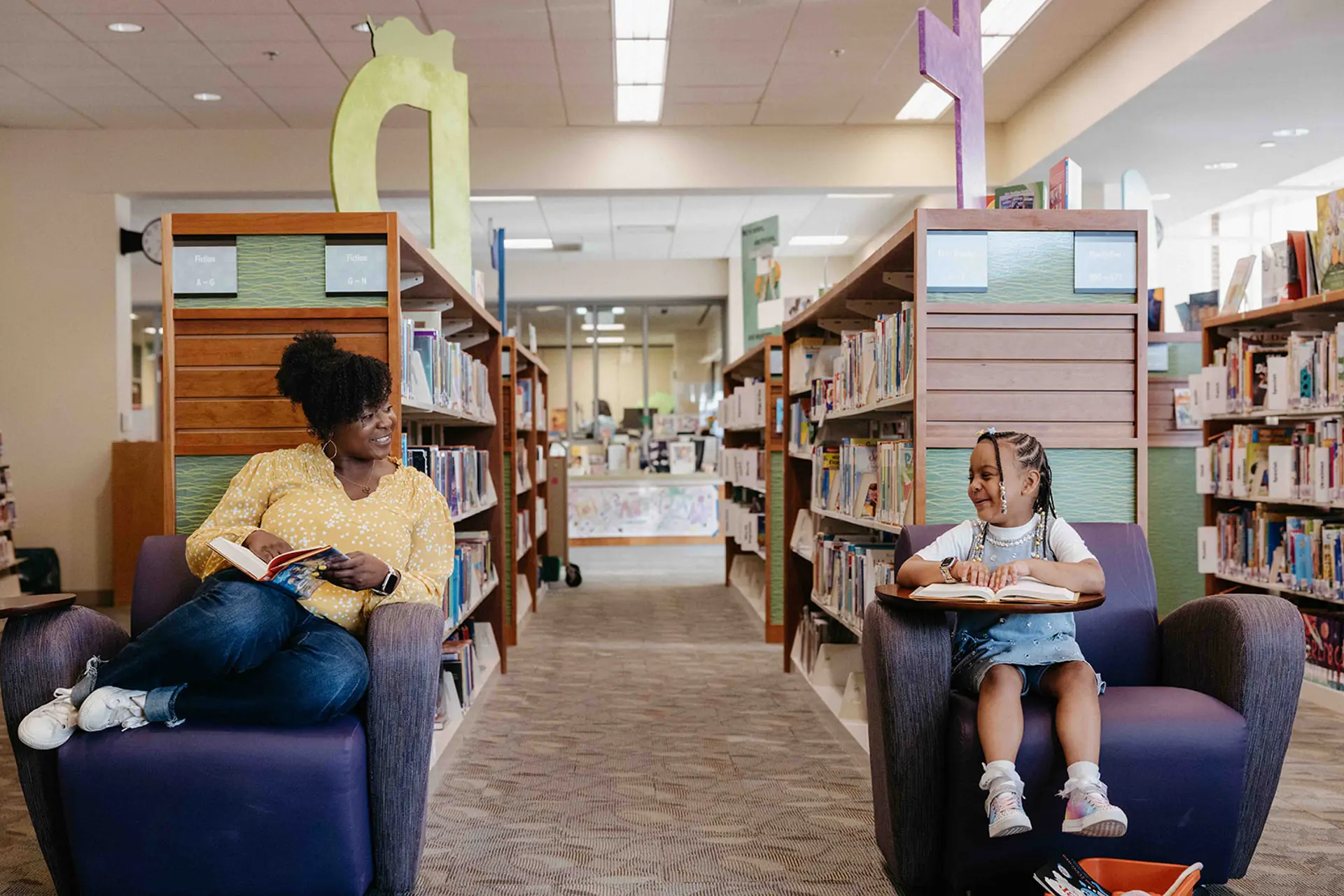 mother and daughter holding books in the library